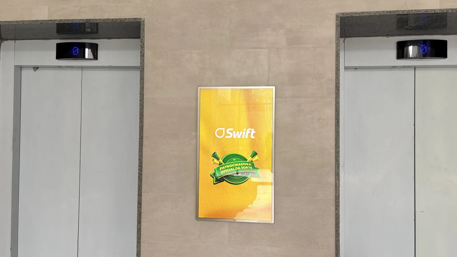 Tela entre elevadores em edifício corporativo